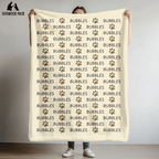 custom dog blanket that is personalized with name and paw print design in plush and sherpa fabric on beige background